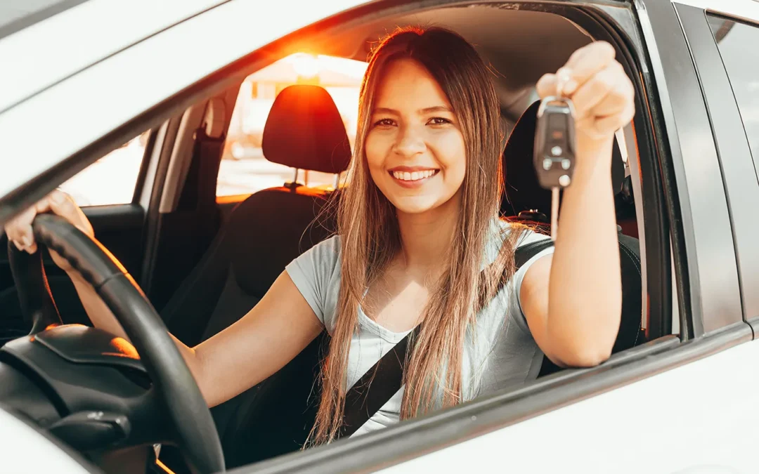 happy young lady teen smiling with car keys sitting in driver's seat of car